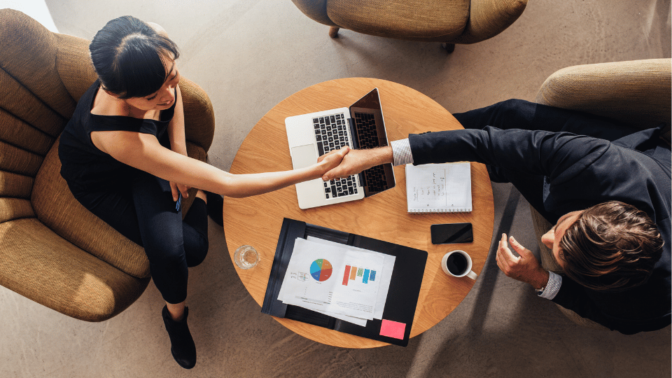 A woman business owner and a business loan provider shaking hands