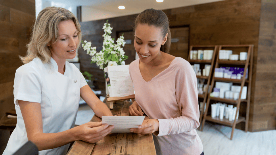 Two girls smiling and interacting in a beauty salon, one works there and the other is a client