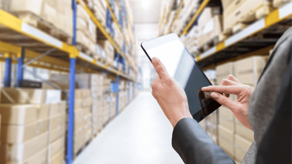 A business owners in a warehouse counting inventory on her tablet
