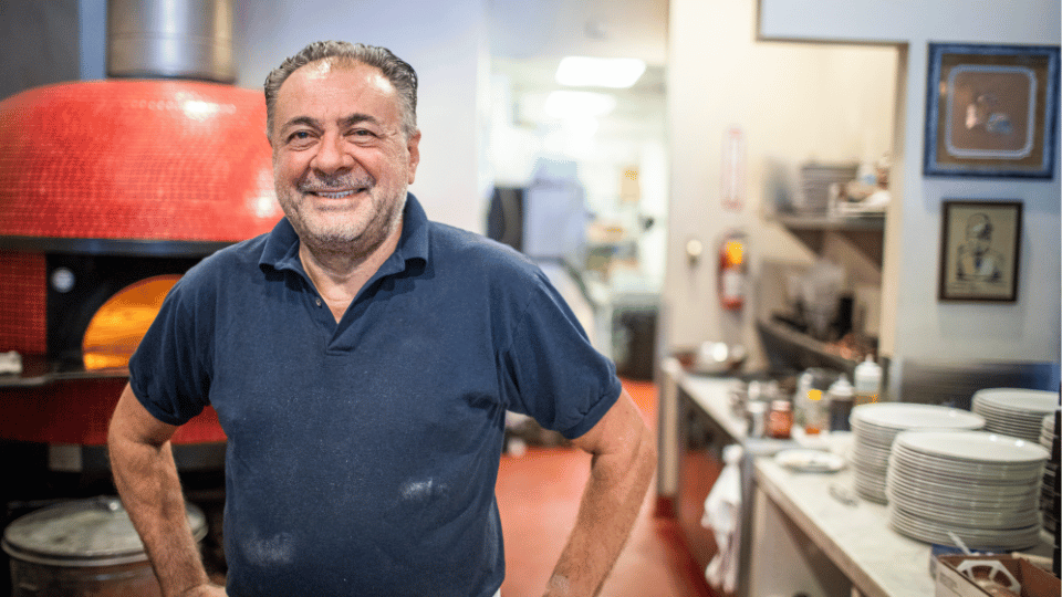 A proud restaurant owner stands in his kitchen, highlighting the success of Hispanic business owners supported by dedicated loan programs.
