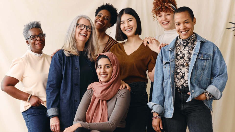 Group of diverse women smiling together in a photo representing inclusivity, with individuals of different ages, ethnicities, and styles, conveying a message of unity and empowerment.