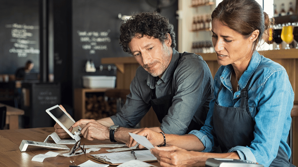 Two business owners, a woman and a man calculating business cash flow