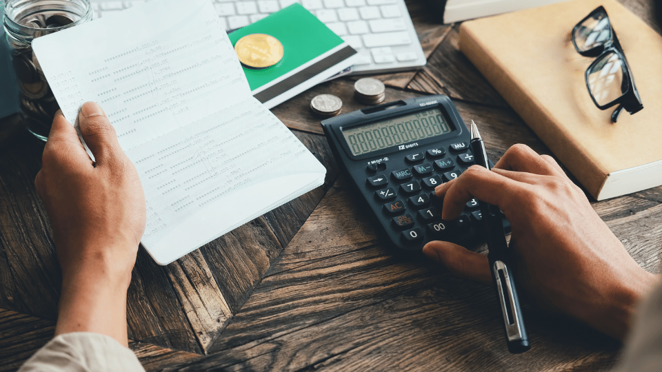 Hand analyzing financial data with a calculator nearby.