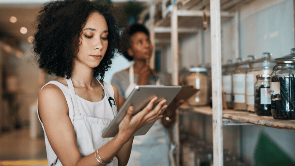 A focused woman using a tablet in a store, highlighting the role of small business loans in empowering women entrepreneurs.